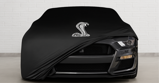 Ford Mustang GT500 covered with a custom-fit indoor cover in a premium garage, partially open on one side.